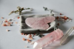 A pink rose quartz gua sha stone and a small crystal with a pouch