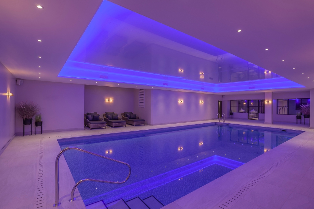 Indoor swimming pool in spa setting with purple lighting